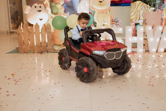 Little boy in a red toy jeep at a jungle-theme first birthday setup, by PickYouPic Prayagraj