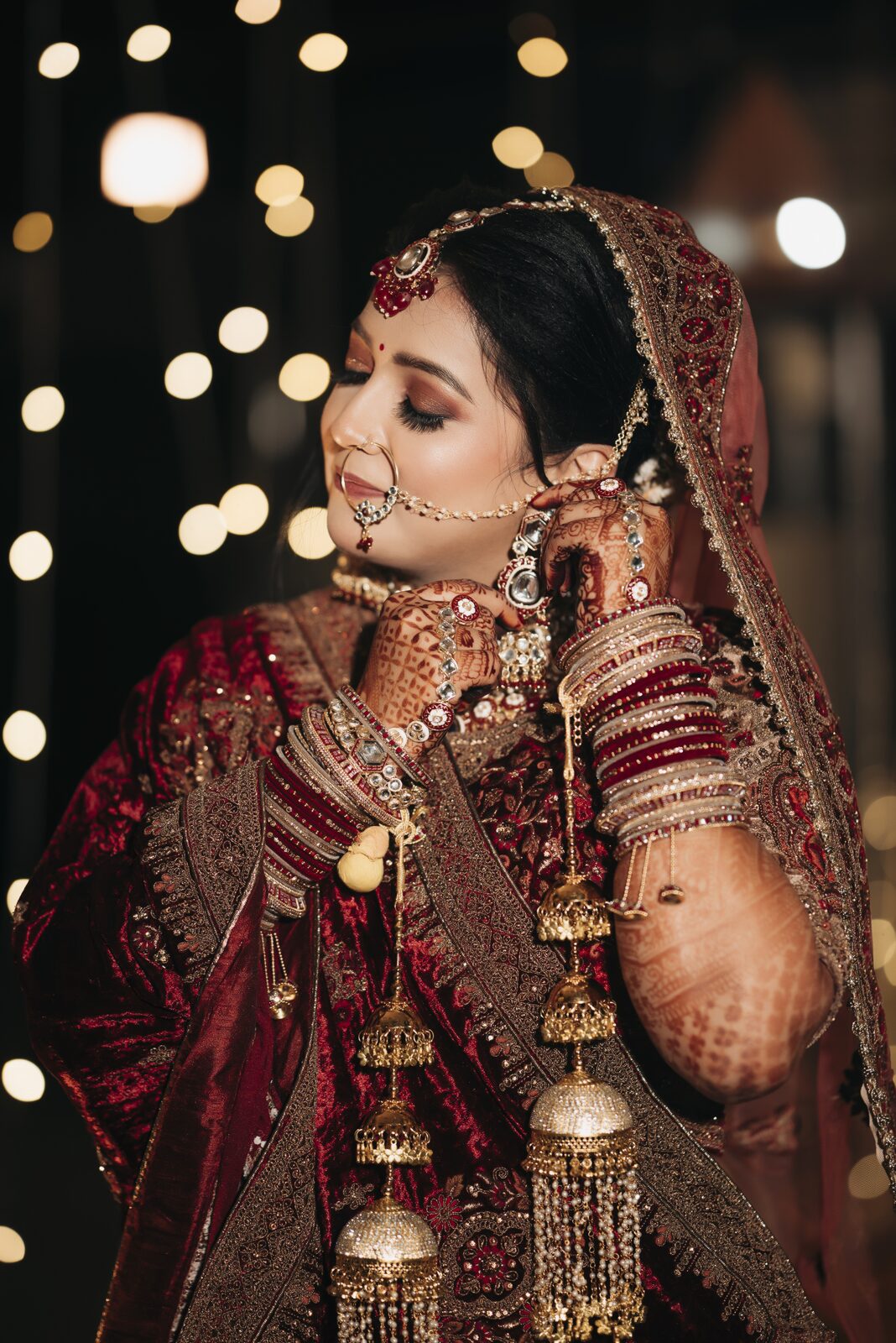 Bride in a red lehenga with jhumka earrings, candid wedding photography in Prayagraj