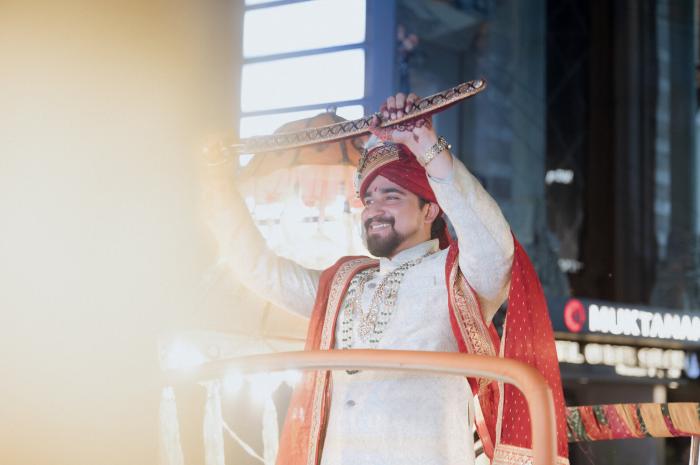 Groom raising his sword during the baraat entry at a Prayagraj wedding
