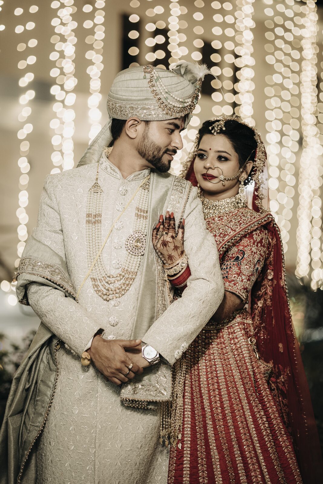 Couple standing under a curtain of hanging lights at their wedding