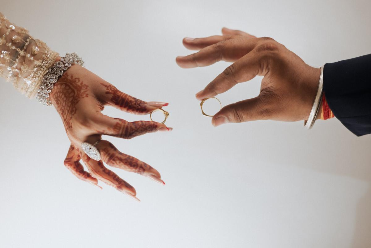 Ring exchange between mehendi-covered hands at a Prayagraj wedding