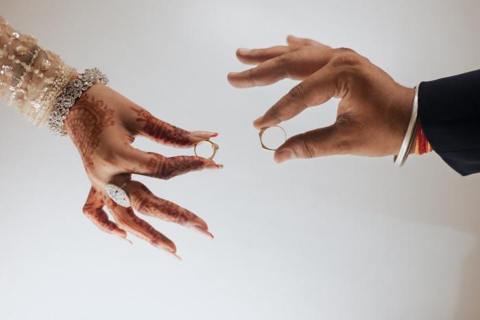 Ring exchange between mehendi-covered hands at a Prayagraj wedding