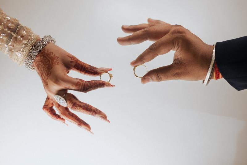 Ring exchange between mehendi-covered hands at a Prayagraj wedding