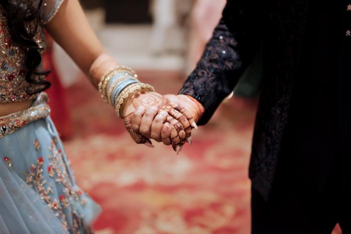 Bride and groom's mehendi-covered hands clasped together, Prayagraj wedding