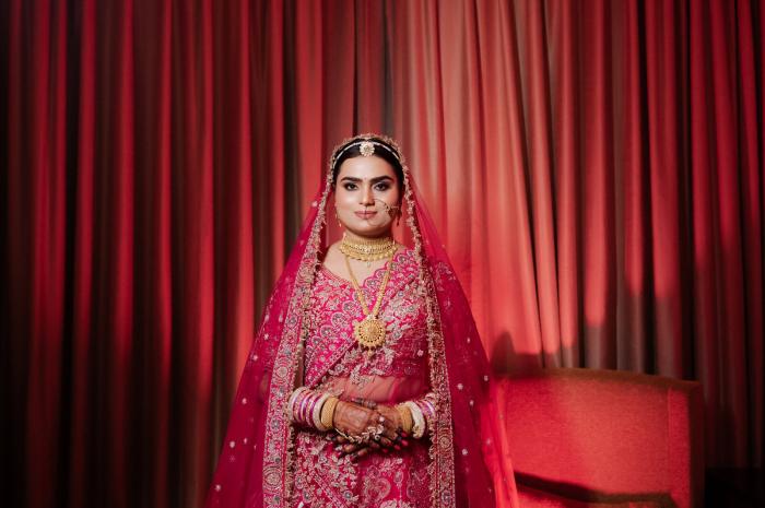 Bride against a deep red curtain on her wedding day, Prayagraj