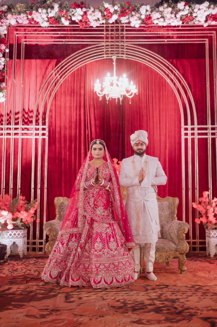 Bride and groom framed by the red wedding arch, Prayagraj