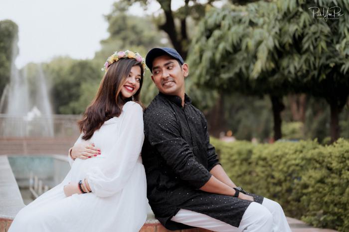 Couple seated together in a park during their maternity shoot, by PickYouPic Prayagraj