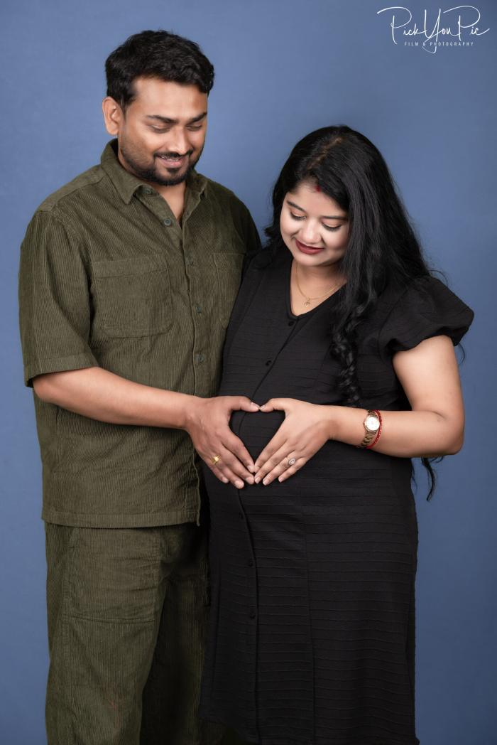 Couple forming a heart with their hands over the baby bump in the studio, maternity photoshoot by PickYouPic Prayagraj