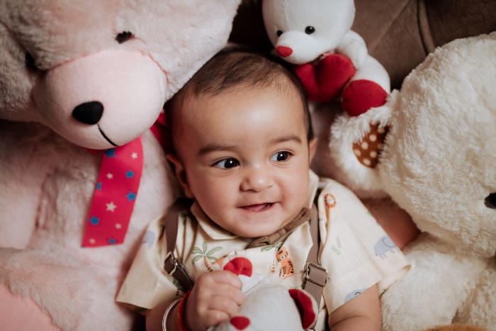 Baby smiling among soft teddy bears, newborn photography by PickYouPic Prayagraj