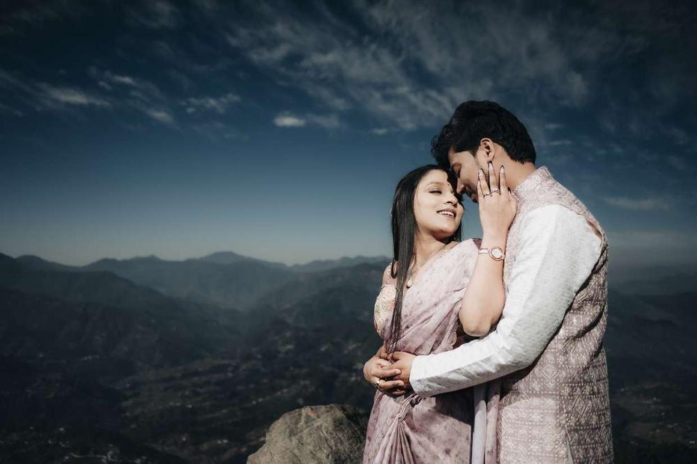 Couple embracing on a hilltop at dusk with a mountain valley behind them