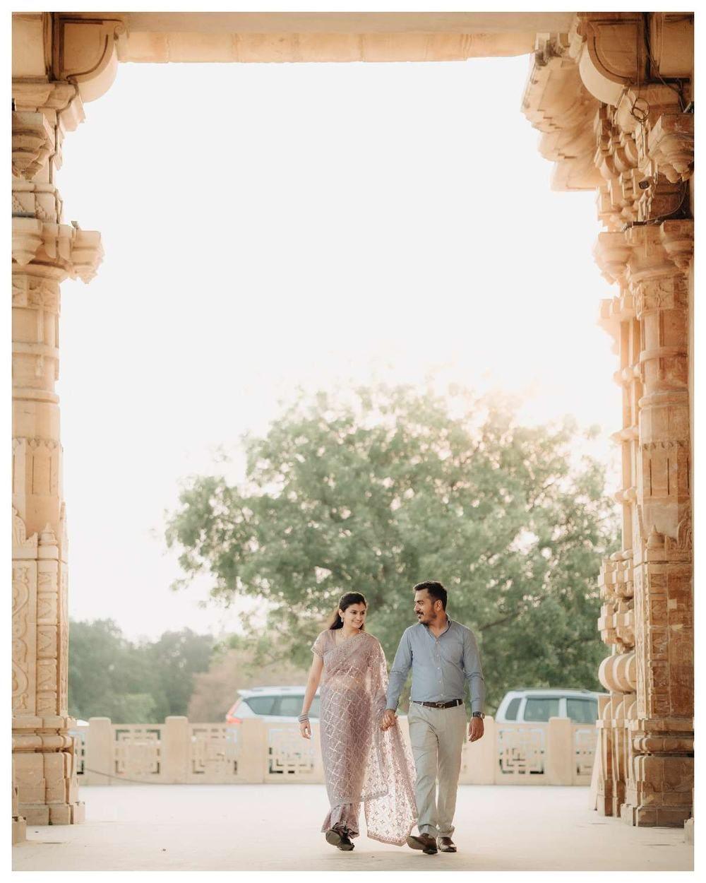 Couple walking through a tall sandstone archway towards the daylight