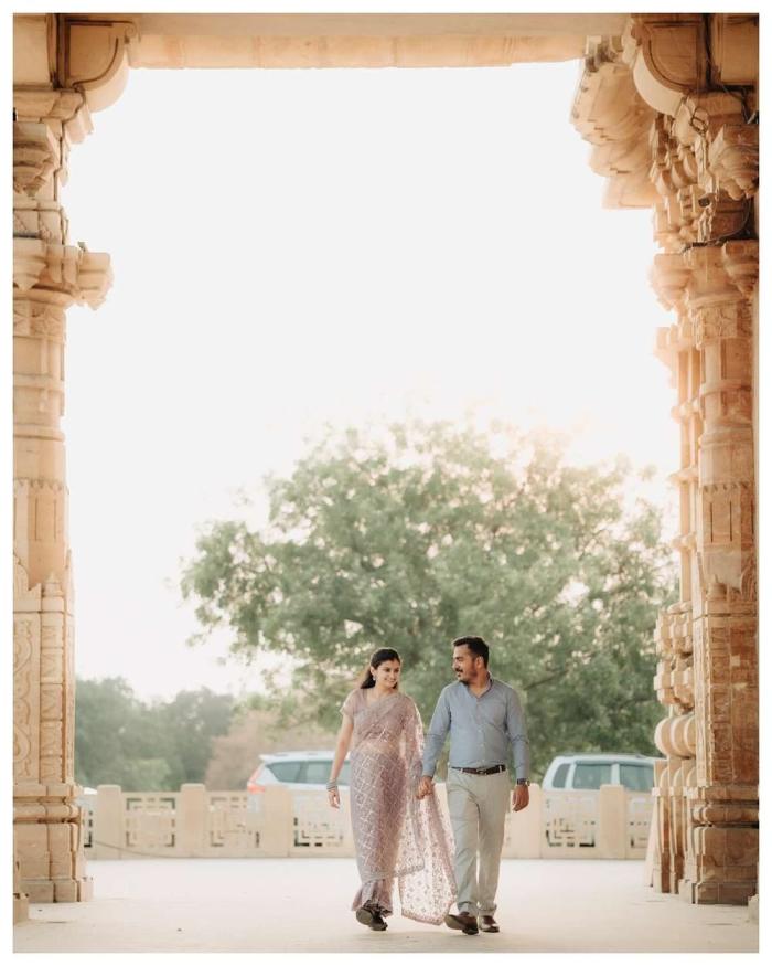 Couple walking through a tall sandstone archway towards the daylight
