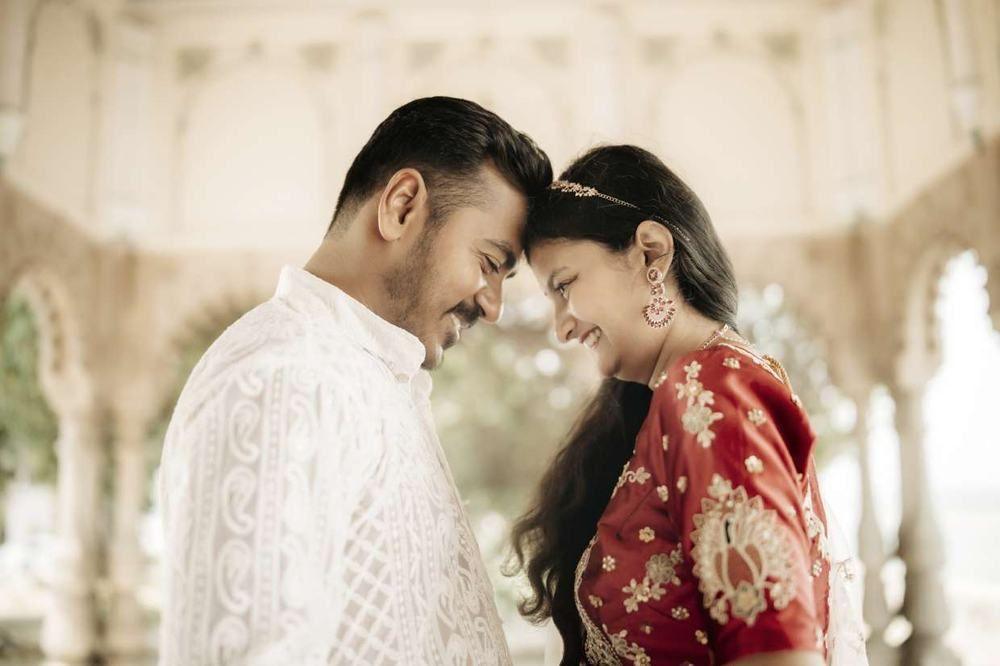 Forehead-to-forehead portrait of a couple under a pillared corridor