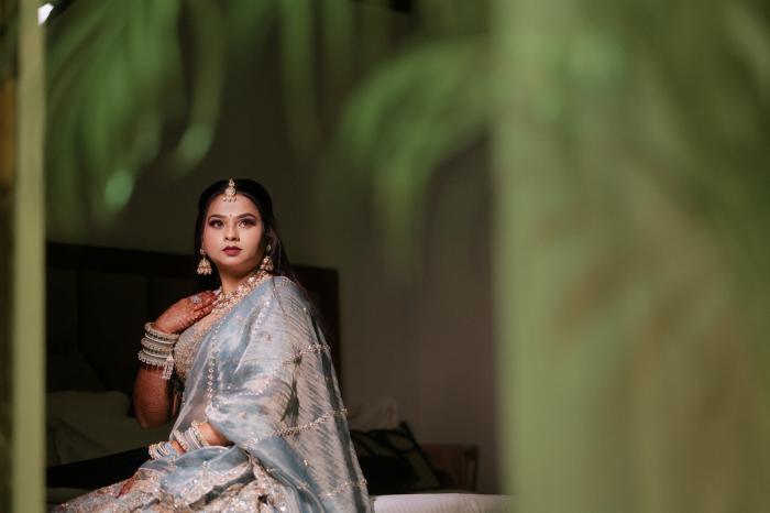 Bride in a silver lehenga framed by greenery, PickYouPic Prayagraj