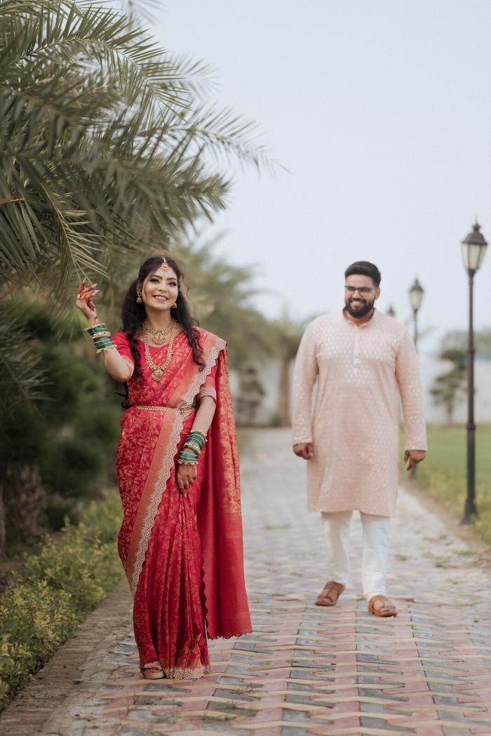 Couple on a palm-lined path in peach and red, Prayagraj