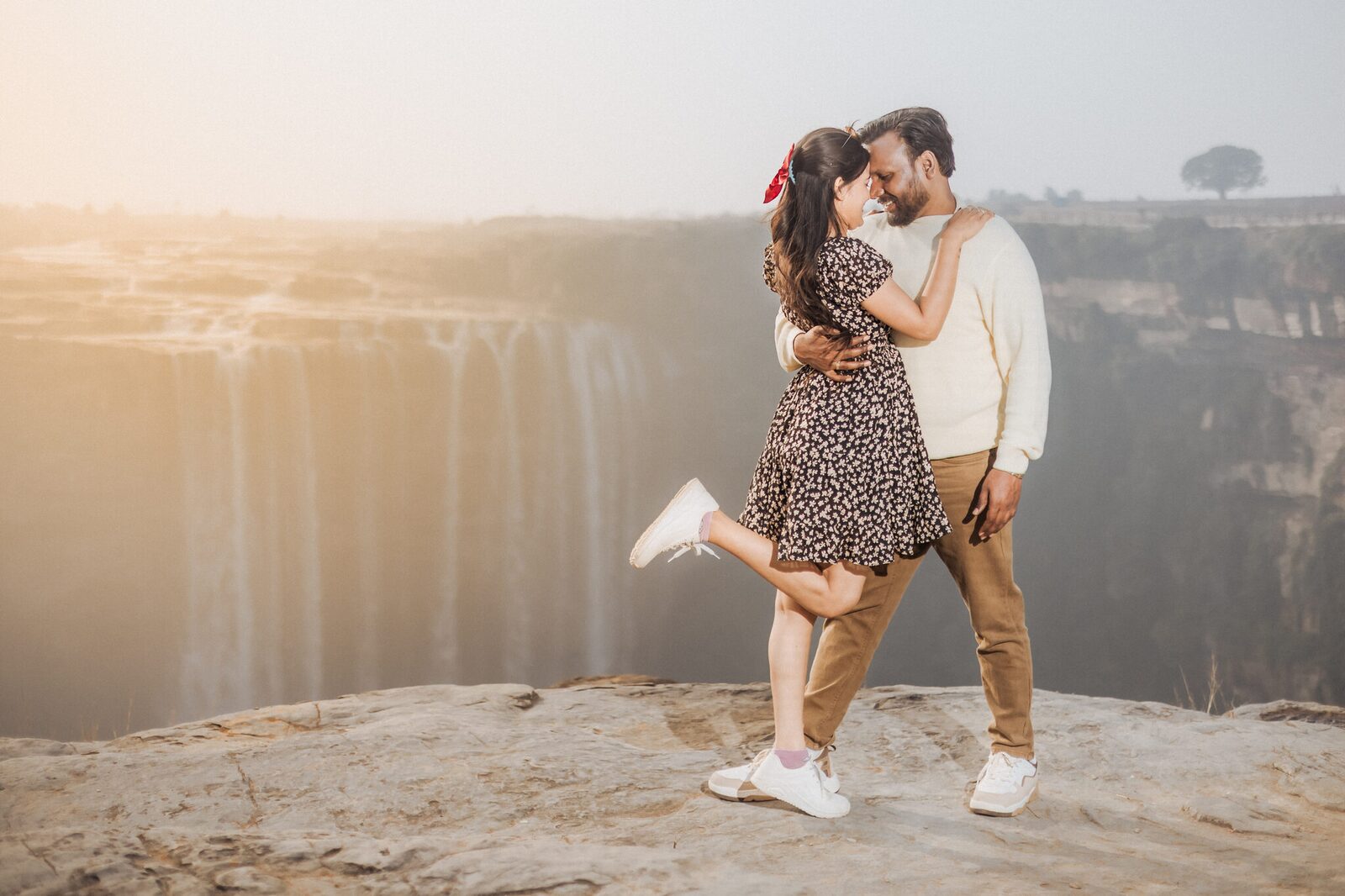 Couple embracing in golden light above Keoti Waterfall