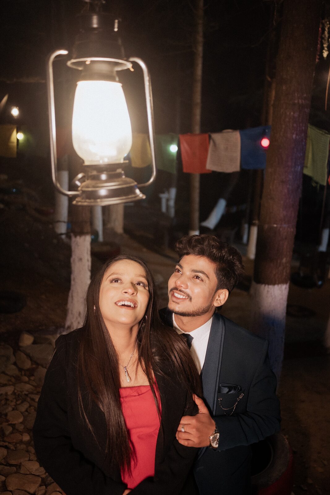 Couple under a hanging lantern and prayer flags at night in Mukteshwar