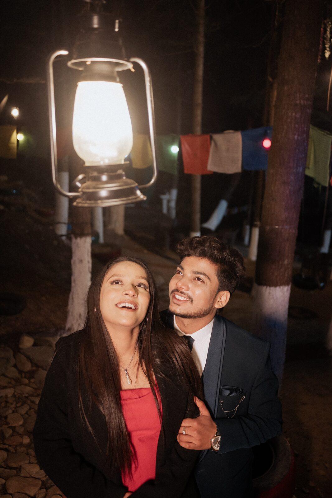 Couple under a hanging lantern and prayer flags at night in Mukteshwar