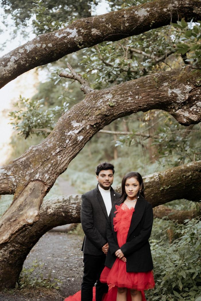 Wide pre-wedding photo beneath an old oak in the Mukteshwar forest, Uttarakhand