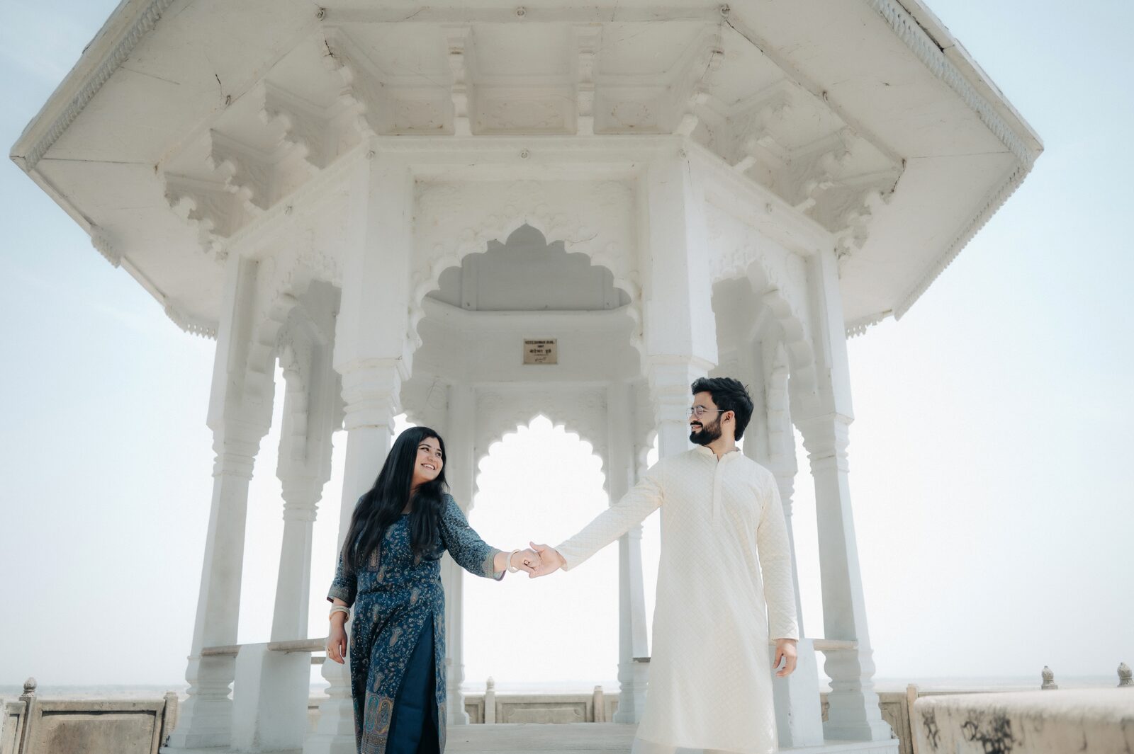 Couple holding hands inside a white marble pavilion, pre-wedding shoot