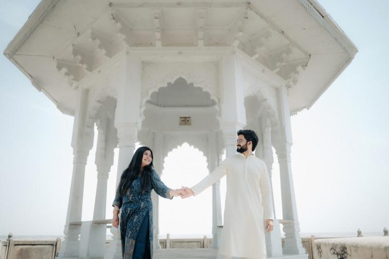 Couple holding hands inside a white marble pavilion, pre-wedding shoot