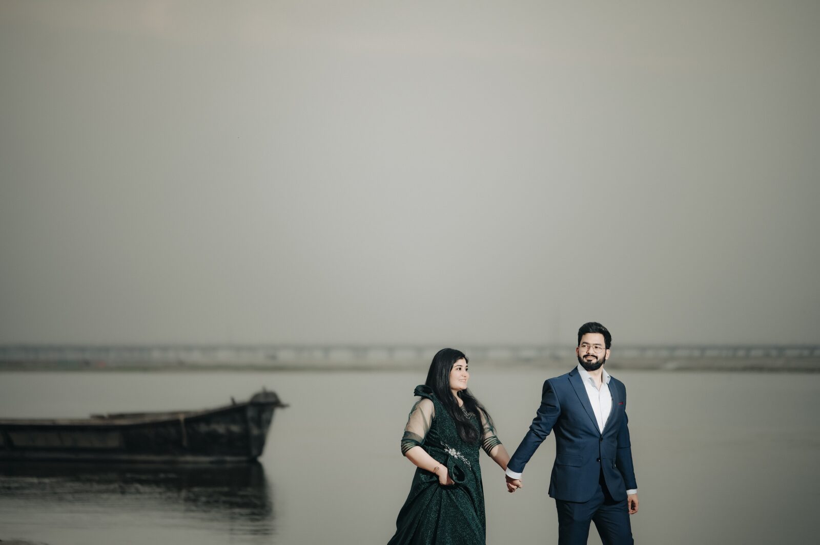 Couple by a wooden boat at the riverside during a pre-wedding shoot