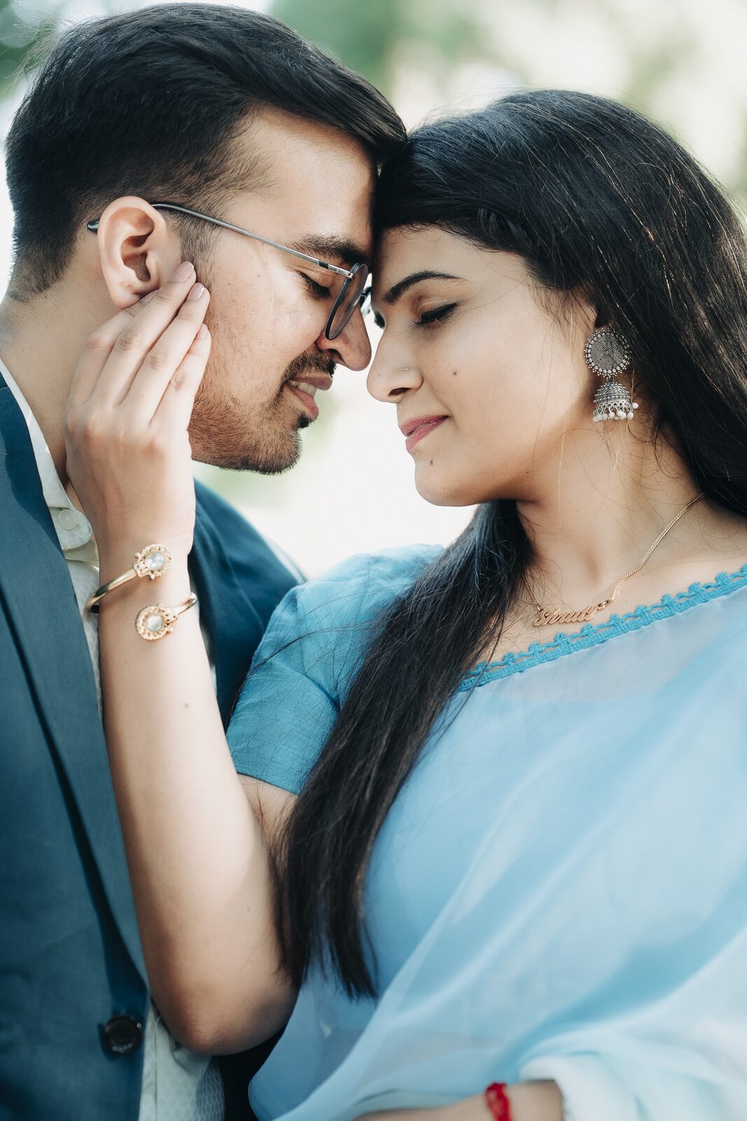 Couple standing forehead to forehead in a blue saree pre-wedding portrait