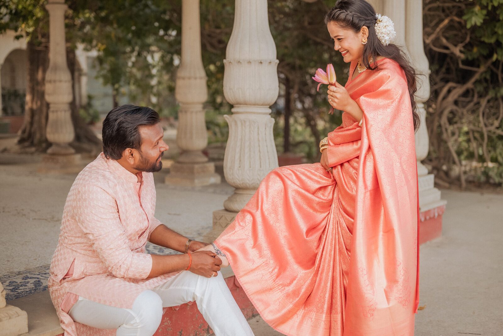 Groom fastening an anklet for his bride in the colonnade at Ram Bagiya, Prayagraj