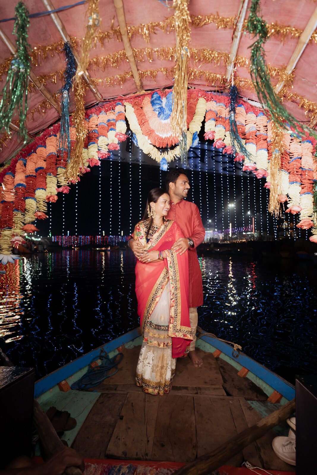 Couple standing at the boat's prow with fairy lights behind, Ram Ghat Chitrakoot