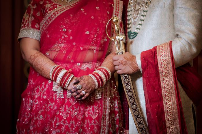 Bride and groom's hands together on the ceremonial sword, Allahabad wedding