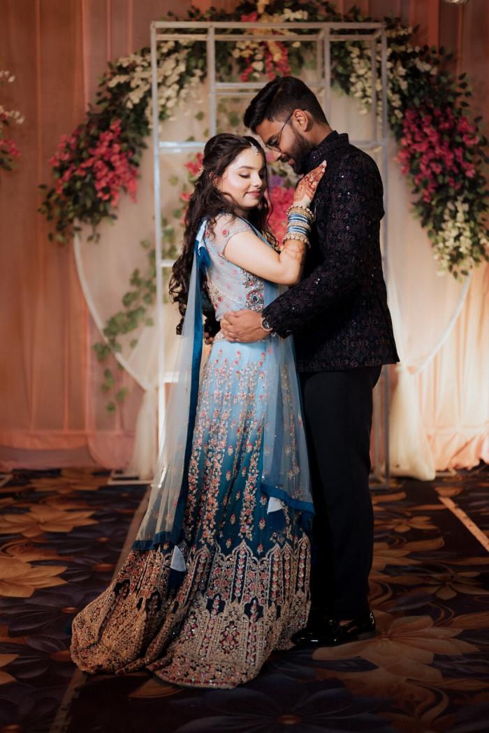 Bride and groom embracing under the floral arch at their wedding, Prayagraj
